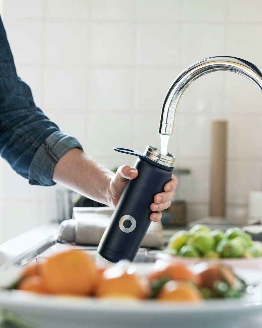 Filling a water bottle from the kitchen tap for testing